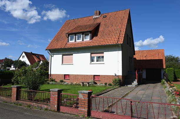 Älteres Einfamilienhaus mit rotem Satteldach unter blauem Himmel